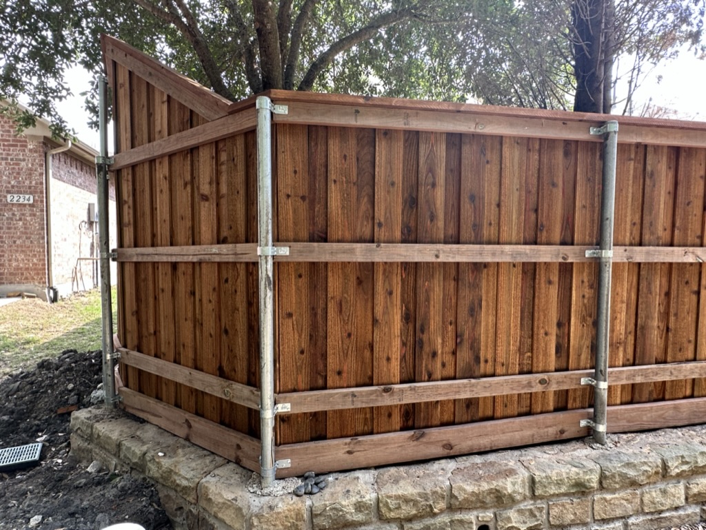 Cap-and-trim cedar fence corner with steel posts in Rockwall County