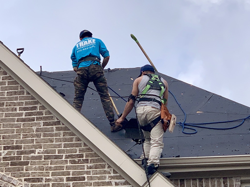 Trake Construction crew tearing off a roof on a Rockwall home