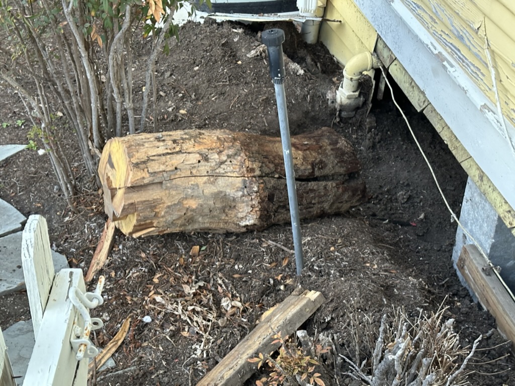 Excavated foundation pier and plumbing access on a historic home repair