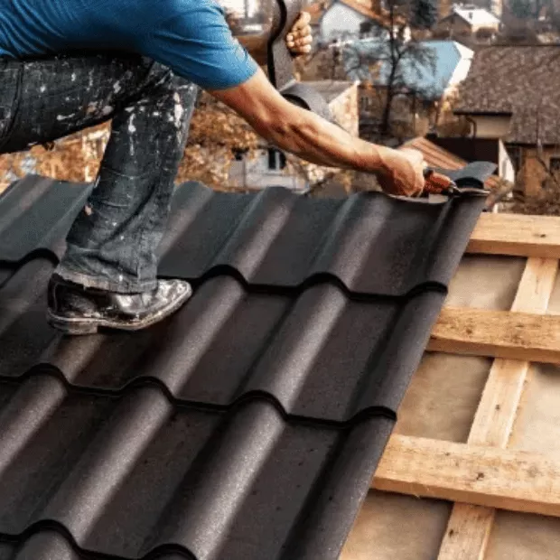 Roofer installing metal tile panels on a residential roof