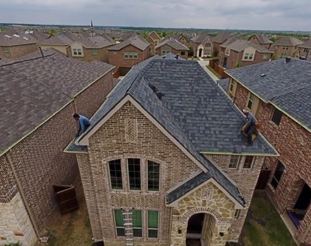 Aerial view of new architectural shingle roof replacement on a Rockwall, TX brick home