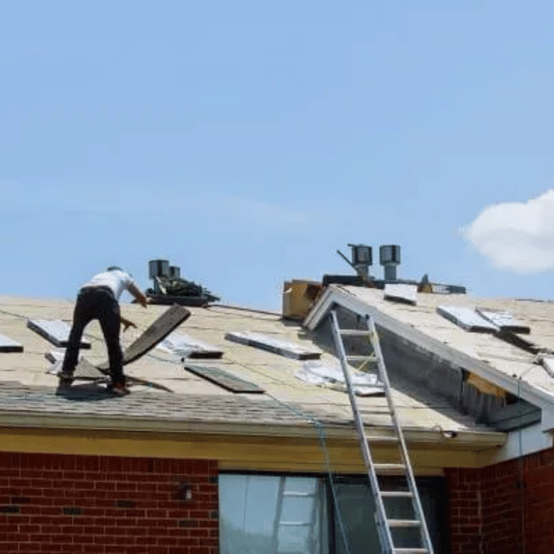 Roofer performing a full tear-off and decking inspection on a Rockwall home